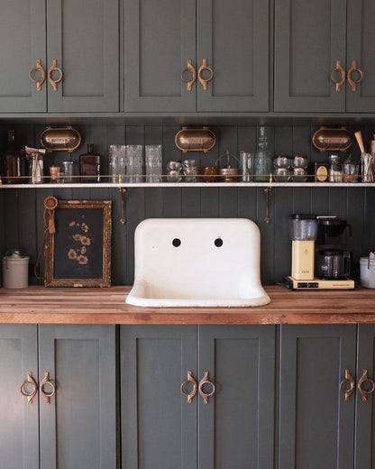 Kitchen with dark green cabinets, wooden countertops, and a white sink.