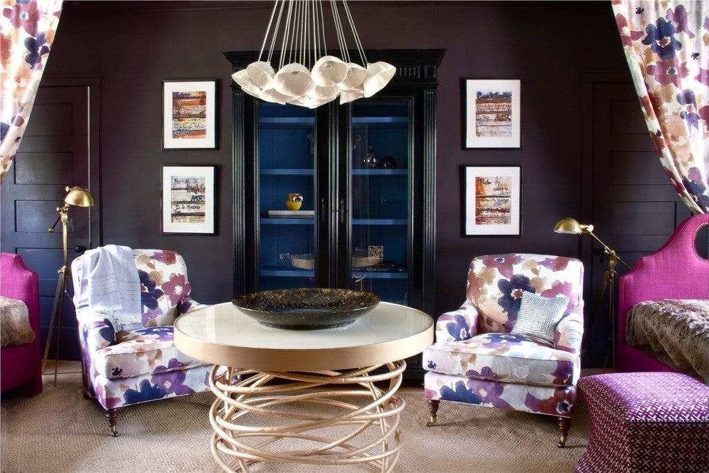Living room with floral armchairs, a round table, and decorative elements.