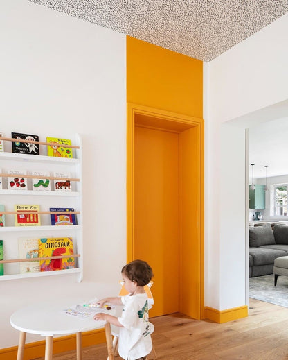 Child playing with toys on a small table in a room with a yellow accent wall.