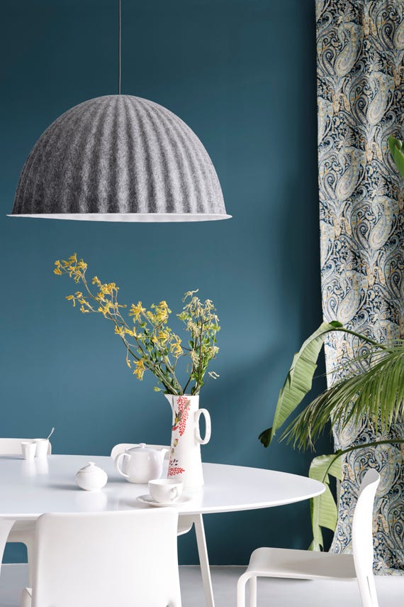 Dining room with a textured pendant light, white table, and patterned curtains.