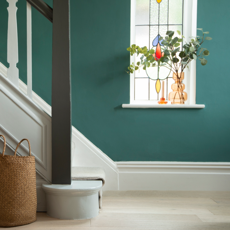 Staircase with teal walls, a window with plants and colorful lights, and a woven basket.