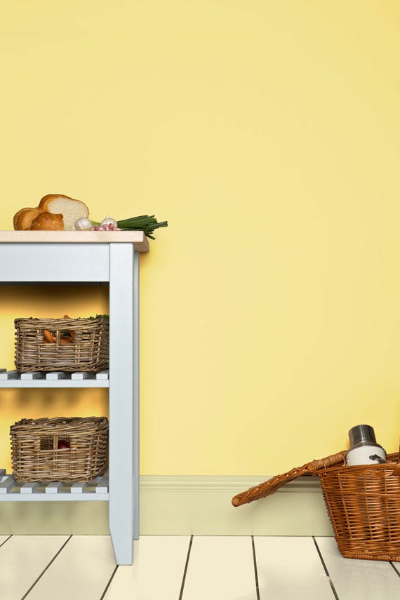 Small white table with wicker baskets against a yellow wall.
