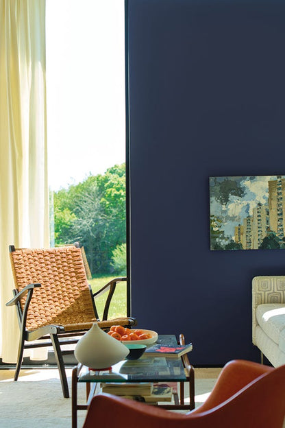 Living room with a blue wall, wicker chair, and modern decor.