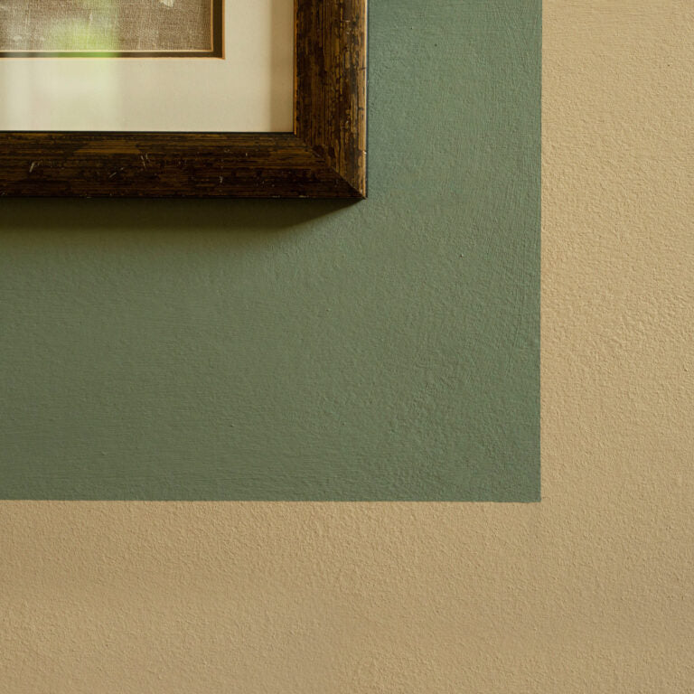 Corner of a wall with a framed picture on a green and beige background