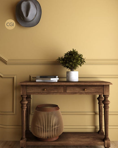 Wooden console table with a plant, basket, and hat against a yellow wall.