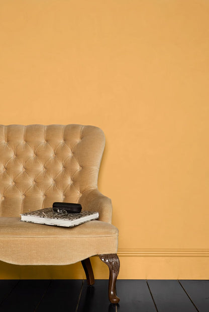 Beige tufted sofa against a mustard yellow wall