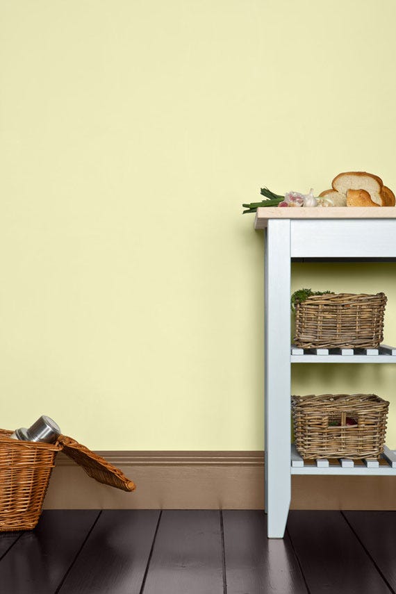 White shelf with wicker baskets against a light yellow wall.
