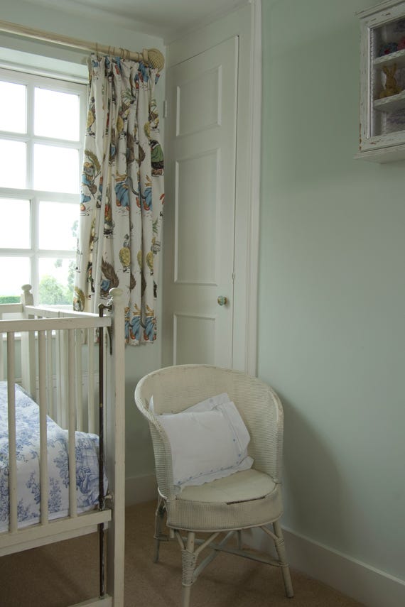 Nursery room with crib, chair, and decorative curtains.