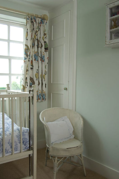 Nursery room with crib, chair, and decorative curtains.