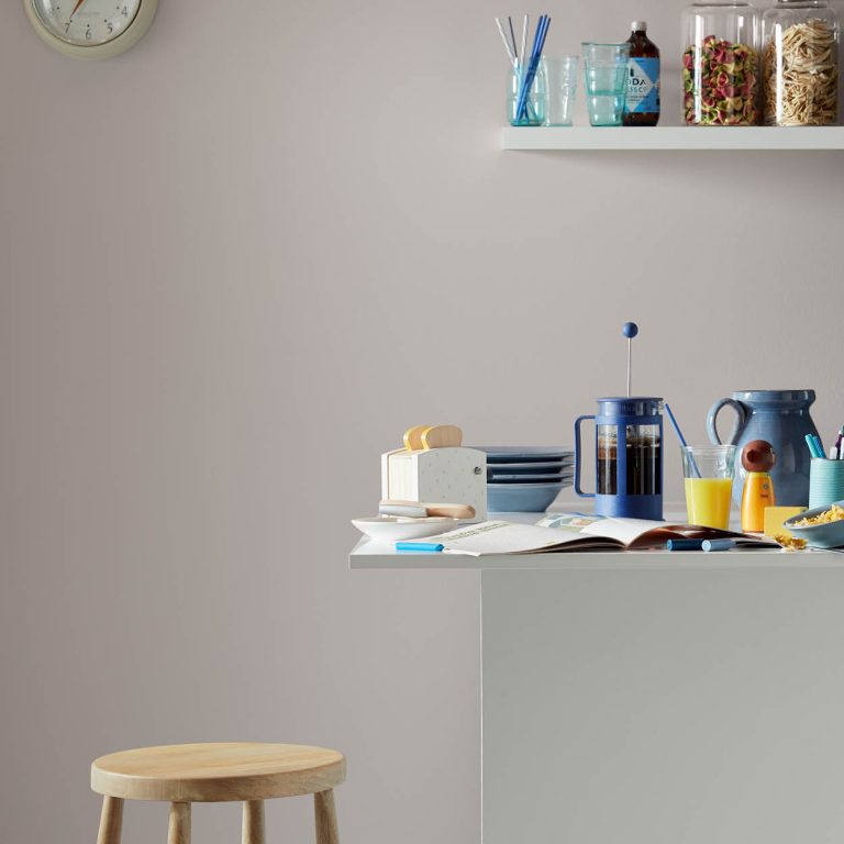 Kitchen counter with coffee maker, books, and snacks against a gray wall.