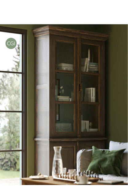 Wooden bookshelf with glass doors in a room with green walls and a window.