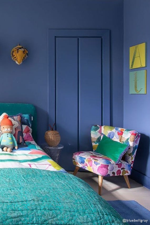 Children's bedroom with blue walls, colorful chair, and bed with toys.