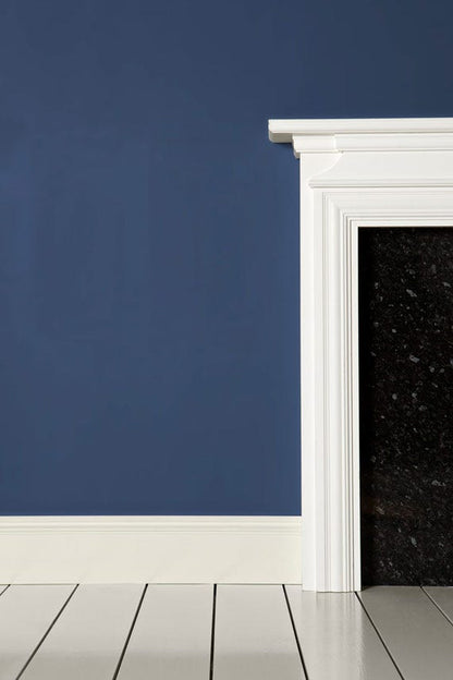 Navy blue wall with white fireplace and wooden floor