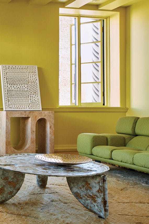 Modern living room with a green sofa, textured coffee table, and yellow walls.
