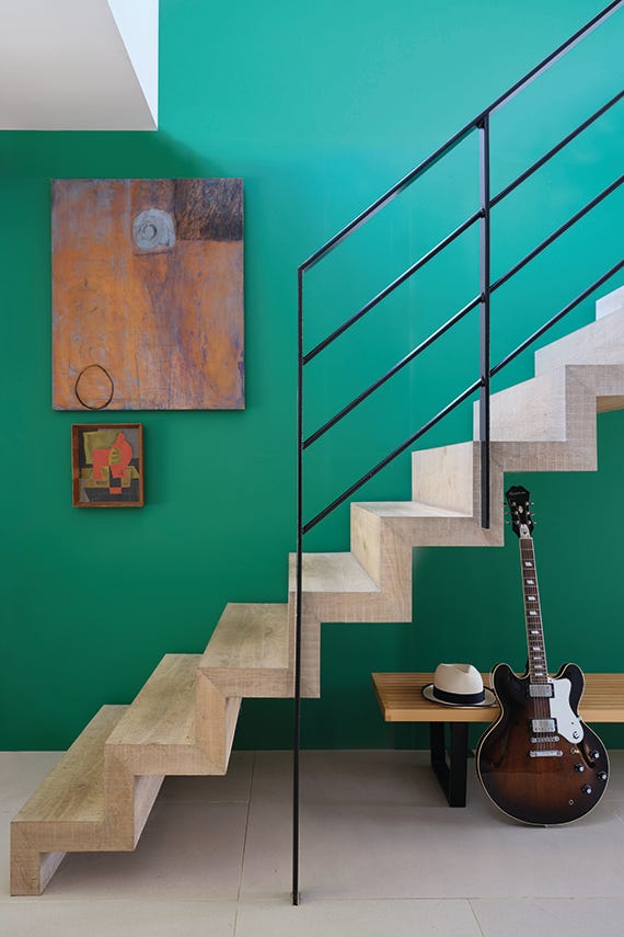Modern staircase with a guitar and hat against a green wall
