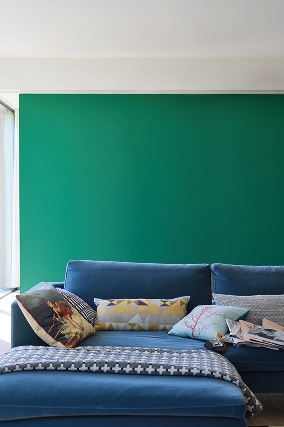 Blue sofa with colorful pillows against a green wall