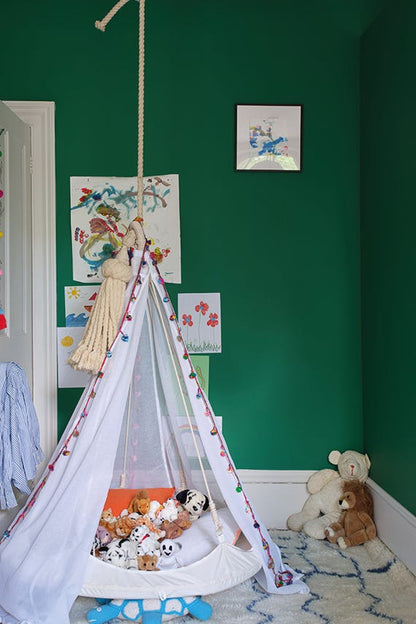 Children's room with green walls, toys, and a hanging crib.
